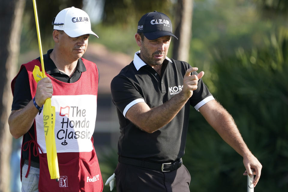 Charl Schwartzel of South Africa, right, talks to his caddie on the eighth hole during the first round of the Honda Classic golf tournament, Thursday, March 18, 2021, in Palm Beach Gardens, Fla. (AP Photo/Marta Lavandier)