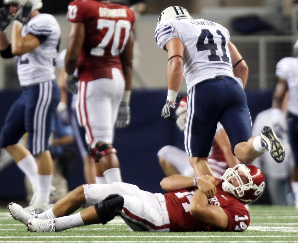 Oklahoma QB Sam Bradford rolls over in pain after being hit and dropped by BYU’s Coleby Clawson at Cowboys Stadium.