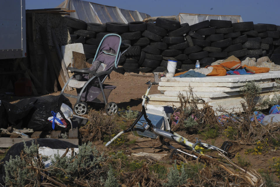 FILE - A children's bicycle and a baby stroller lay inside a squalid makeshift living compound in Amalia, N.M., on Aug. 10, 2018. Two firearms charges were dismissed Thursday, Sept. 21, 2023, amid preparations for trial against an extended family arrested in a 2018 law enforcement raid on the compound in northern New Mexico and the discovery of a young boy's decomposed body. (AP Photo/Morgan Lee, File)