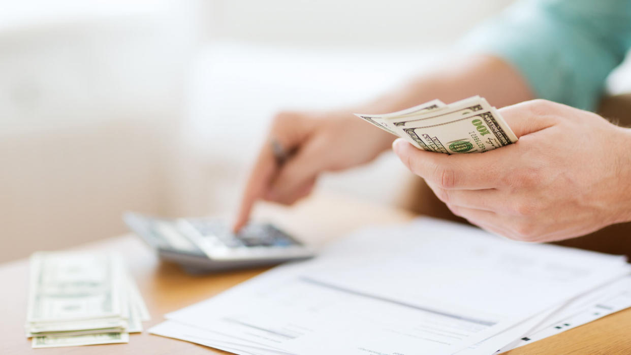 man with calculator counting money and making notes at home