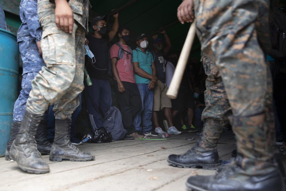 Honduras migrants stand in an army truck before returning home, in Morales, Guatemala, Saturday, Oct. 3, 2020. Early Saturday, hundreds of migrants who had entered Guatemala this week without registering were being bused back to their country's border by authorities after running into a large roadblock. (AP Photo/Moises Castillo)