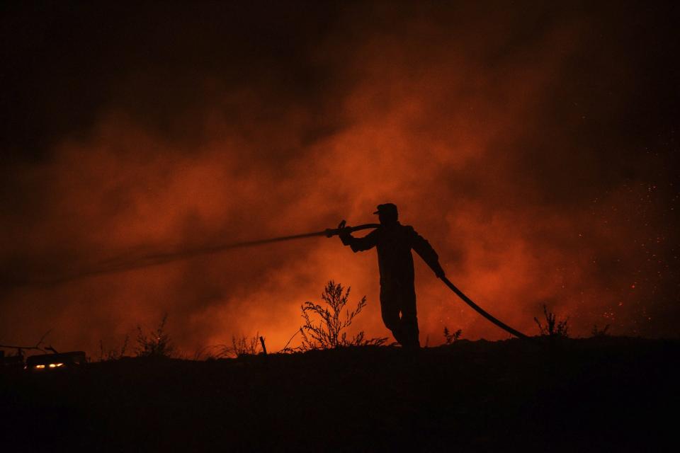 A firefighter battles with fire in Kirli village near the town of Manavgat, in Antalya province, Turkey early Friday July 30, 2021. The fire that continued all night could not be brought under control and people living in the village started to evacuate. Wildfires are common in Turkey's Mediterranean and Aegean regions during the arid summer months, although some previous forest fires have been blamed on arson.(AP Photo)