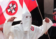 <p>A member of the Ku Klux Klan taunts protesters at a rally in Greensburg, Pa., August 16, 1997. Police, who kept several hundred people from interfering with the rally, were unable to keep some protesters from throwing eggs, bottles and debris at the Klan members. (Photo: Gary Tramontina/AP) </p>