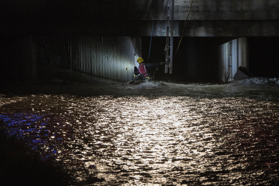 A Clark County Fire Department official searches for a man who was trapped in floodwaters in a flood channel Friday, Sept. 1, 2023, in Las Vegas. (AP Photo/John Locher)
