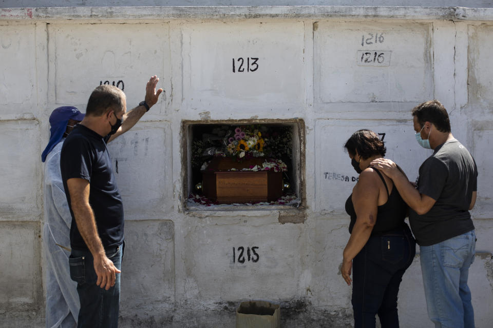 Carlos Alberto holds out his left arm during the burial service for his 41-year-old wife Aparecida de Freitas, who died from complications related to COVID-19, in the Inhauma cemetery, in Rio de Janeiro, Brazil, Thursday, April 15, 2021. (AP Photo/Bruna Prado)