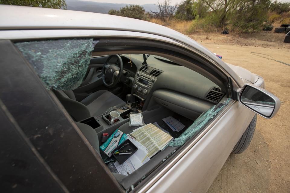 The broken passenger window of a car on the property.