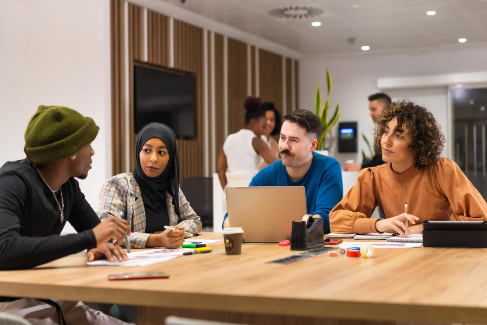 Workers talking at common coworking space tables, busy multiethnic businessmen and businesswomen working together in the space of coworking, diverse staff of employees