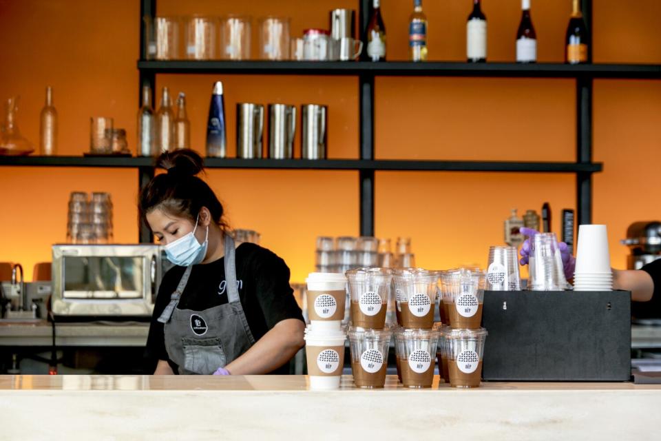 A woman stands behind the counter at a coffee shop.