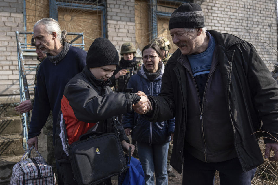 Myroslav, shakes hand with his neighbour during an evacuation by Ukrainian police, in Avdiivka, Ukraine, Tuesday, March 7, 2023. For months, authorities have been urging civilians in areas near the fighting in eastern Ukraine to evacuate to safer parts of the country. But while many have heeded the call, others -– including families with children -– have steadfastly refused.(AP Photo/Evgeniy Maloletka)