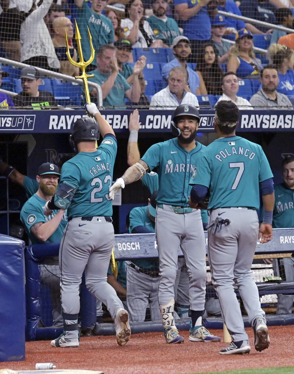 Seattle Mariners ' J.P. Crawford, center, greets Ty France (23) and Jorge Polanco (7) at the dugout after France's two-run home run off Tampa Bay Rays starter Zack Littell during the fifth inning of a baseball game Tuesday, June 25, 2024, in St. Petersburg, Fla. (AP Photo/Steve Nesius)