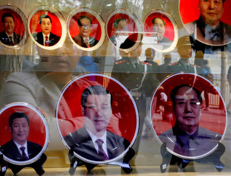 FILE PHOTO - Paramilitary policemen and pedestrians are reflected on the shop window of a shop selling souvenirs bearing the pictures of China's President Xi Jinping (L) and former leaders near the Great Hall of the People in Beijing October 23, 2014. REUTERS/Kim Kyung-Hoon/File Photo