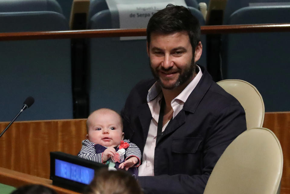 Clarke Gayford sujeta a su bebé mientras que Jacinda Ardern interviene en Naciones Unidas (REUTERS/Carlo Allegri).