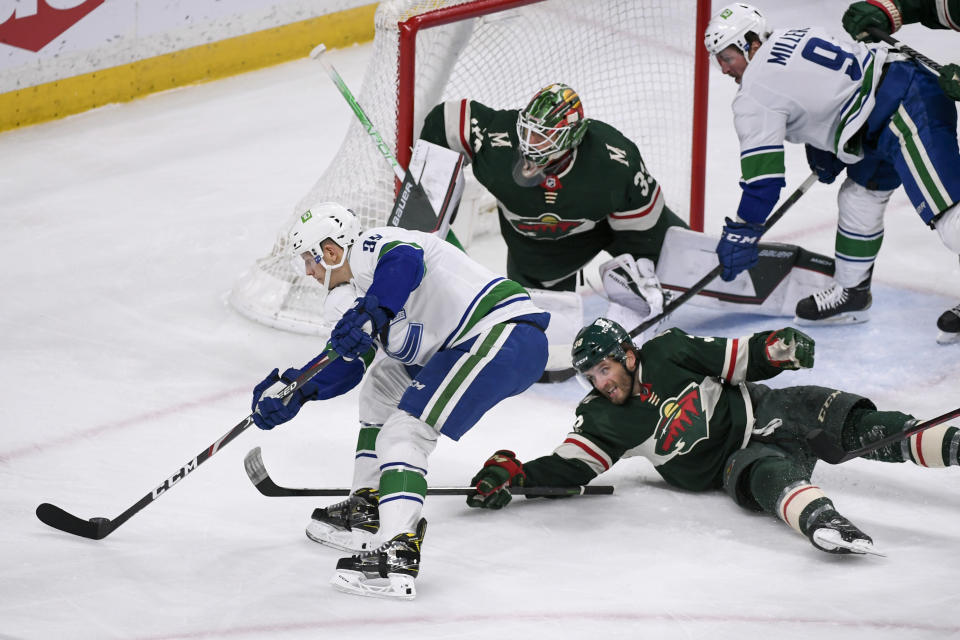 Vancouver Canucks right winger Alex Chiasson, left, tries to get the puck past Minnesota Wild right wing Ryan Hartman, right, and goalie Cam Talbot during the first period of an NHL hockey game Thursday, April 21, 2022, in St. Paul, Minn. (AP Photo/Craig Lassig)