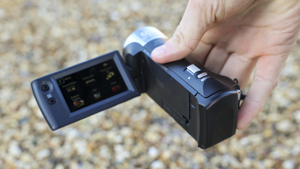 The Sony HDR-CX405 camcorder held low in a man's hand