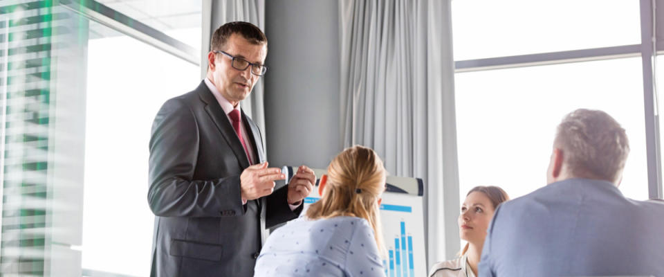 Mature businessman discussing with colleagues in board room