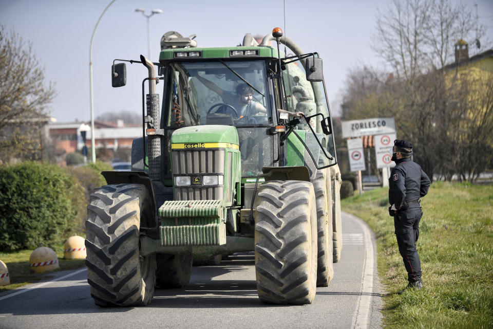 A Carabinieri (Italian paramilitary police) officer talks to a farmer on a tractor at a road block in Zorlesco, Northern Italy, Monday, Feb. 24, 2020. Italy scrambled to check the spread of Europe's first major outbreak of the new viral disease amid rapidly rising numbers of infections. Road blocks were set up in at least some of 10 towns in Lombardy at the epicenter of the outbreak, to keep people from leaving or arriving. (Claudio Furlan/Lapresse via AP)