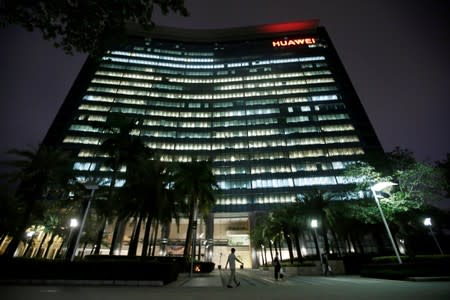 FILE PHOTO: Employees walk past a research and development building with lights on at Huawei headquarters in Shenzhen