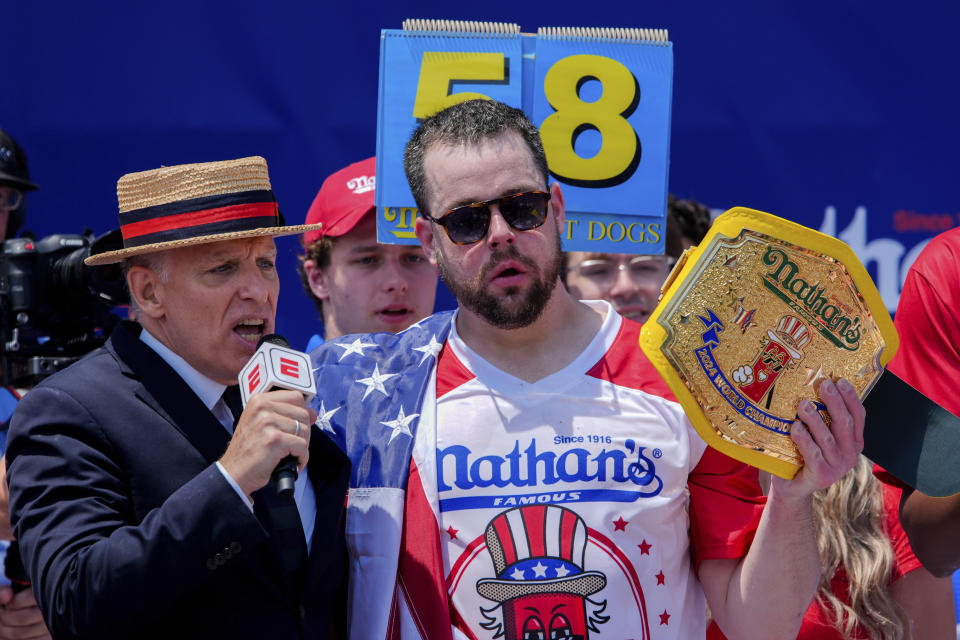 Patrick Bertoletti, right, reacts after winning the men's division in Nathan's Famous Fourth of July hot dog eating contest, Thursday, July 4, 2024, at Coney Island in the Brooklyn borough of New York. Bertoletti ate 58 hot dogs. (AP Photo/Julia Nikhinson)