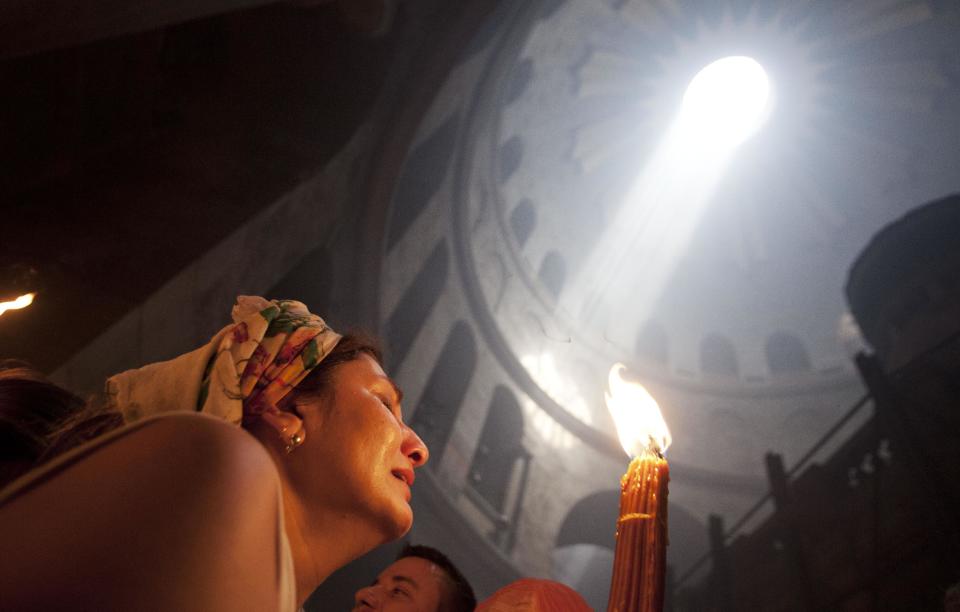 A Christian pilgrim holds candles at the church of the Holy Sepulcher, traditionally believed to be the burial site of Jesus Christ, during the ceremony of the Holy Fire in Jerusalem's Old City, Saturday, April 19, 2014. The "holy fire" was passed among worshippers outside the Church and then taken to the Church of the Nativity in the West Bank town of Bethlehem, where tradition holds Jesus was born, and from there to other Christian communities in Israel and the West Bank. (AP Photo/Dan Balilty)