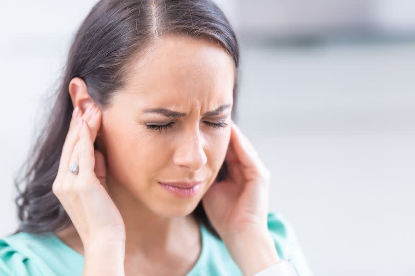 Young woman have headache migraine stress or tinnitus - noise whistling in her ears.