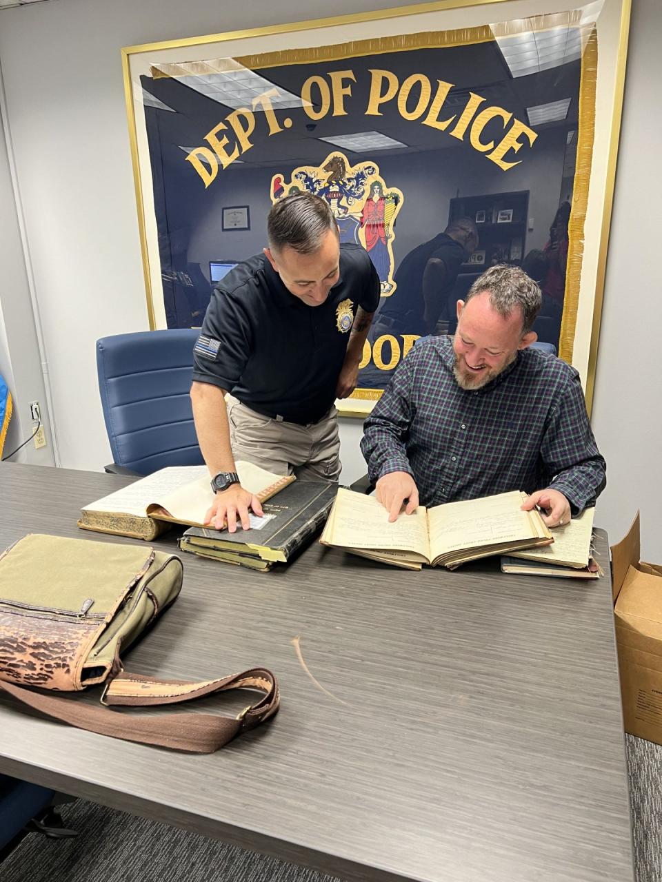 David Colman, an associate professor at Ramapo College, is looking over Englewood Police Department logs dating back to 1899 with Englewood Police Chief Tom Greeley. Colman plans to digitize the logs as part of a project related to Black and immigrant history in Englewood.