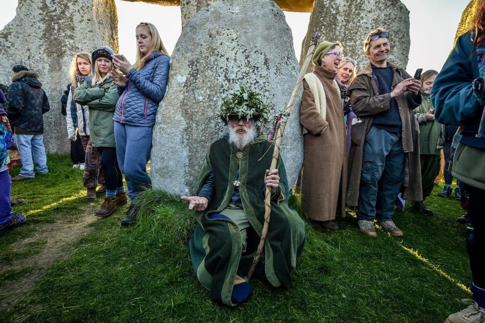 A druid rests in the stone circle at Stonehenge where people gather to celebrate the dawn of the longest day in the UK