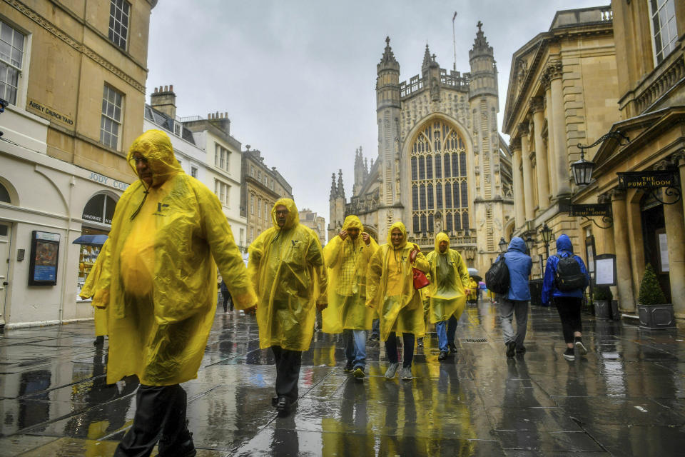 Tourists wear ponchos as they cross Bath Abbey churchyard during a downpour in the centre of Bath, England, Friday June 7, 2019.  (Ben Birchall/PA via AP)