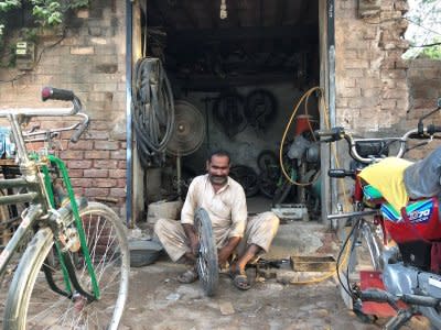 A man fixes a motorcycle tyres at his workshop in the town of Rabwah, Pakistan July 9, 2018. Picture taken July 9, 2018. REUTERS/Saad Sayeed