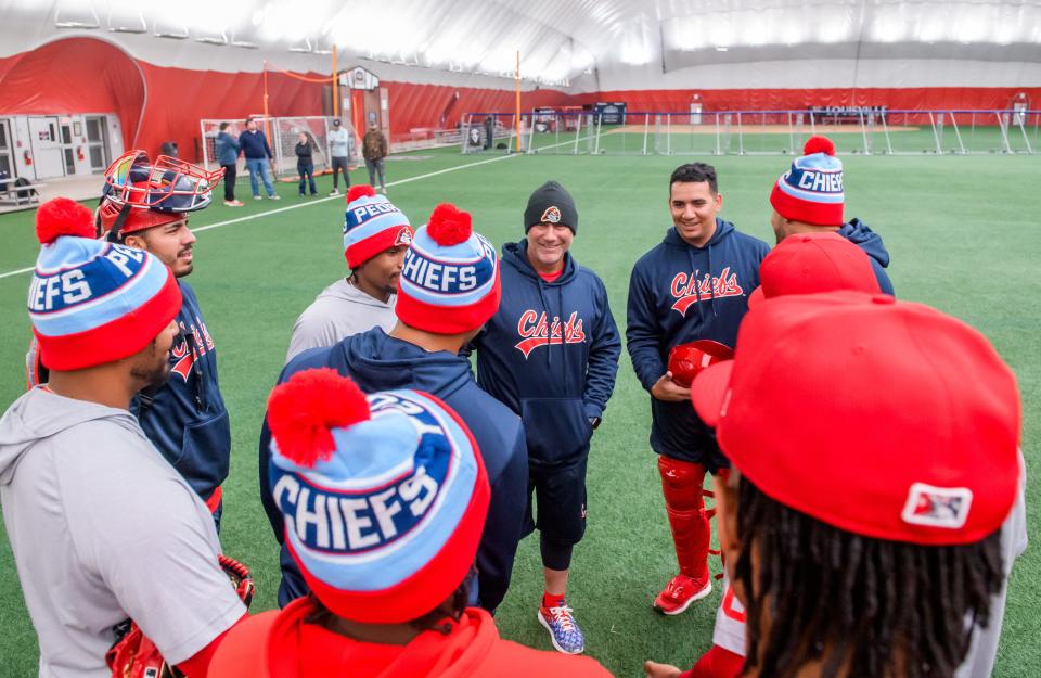 Peoria Chiefs manager Patrick Anderson, middle in stocking cap, talks with a group of his pitchers during practice Wednesday, April 4, 2024 at the Louisville Slugger dome in Peoria.