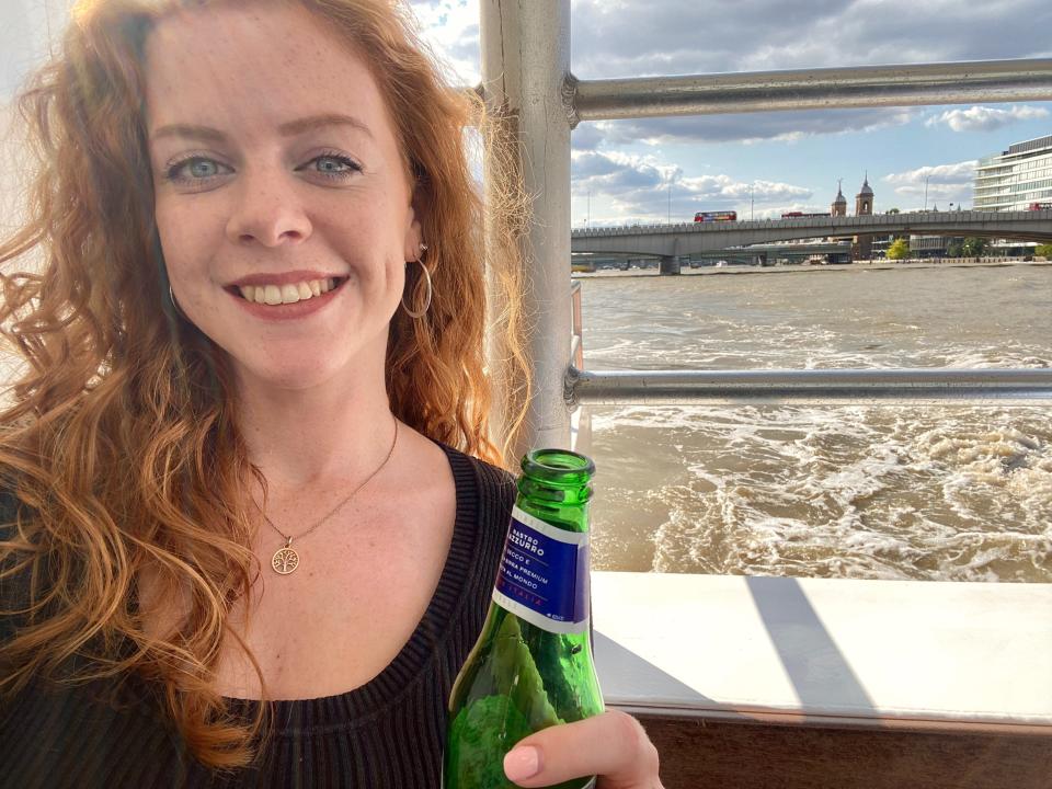 Selfie of reporter Kate Duffy holding a beer at the back of the boat