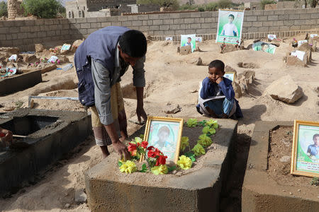 Abdullah al-Khawlani puts roses on the grave of his son, Waleed, who was killed by last month's Saudi-led air strike that killed dozens including children in Saada, Yemen September 4, 2018. His other son, Hafidh, who survived the strike, looks on. REUTERS/Naif Rahma