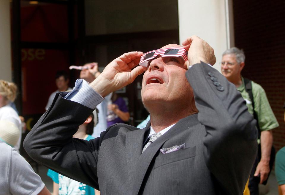 Ashland University president Carlos Campo views the eclipse through a pair of solar viewing glasses at the Solar Eclipse viewing party at the Ashland University Library Monday, Aug. 21, 2017. TOM E. PUSKAR/ASHLAND TIMES-GAZETTE