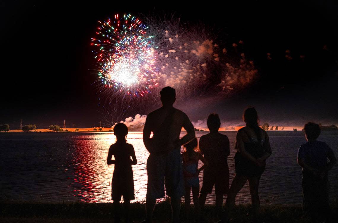 A family watches the Fourth of July fireworks presentation at Woodward Reservoir in Oakdale, Calif., Saturday, July 1, 2023.