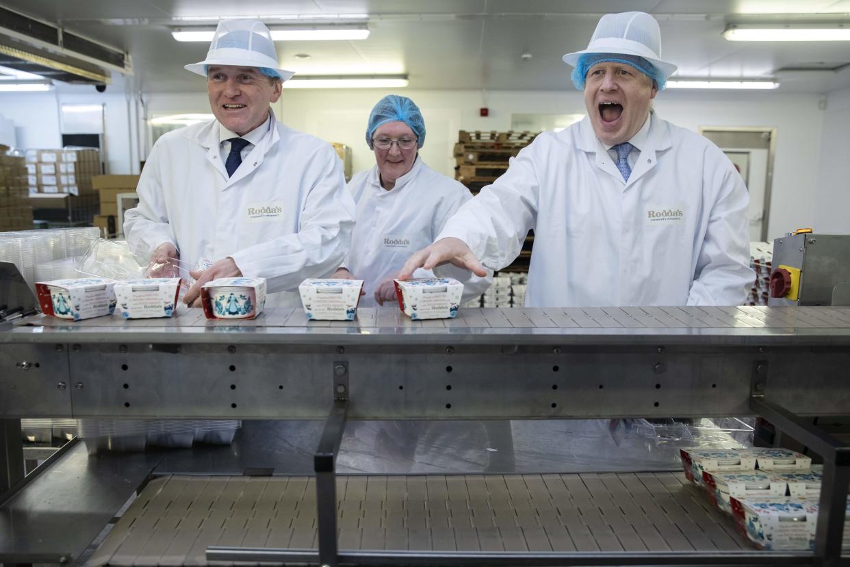 TOPSHOT - Britain's Prime Minister Boris Johnson (R) and Conservative MP George Eustice (L) react during a visit to Cornish Clotted Cream manufacturer 