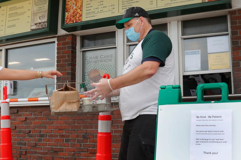 Chris Dotoli hands an order to a customer Wednesday outside Kelly’s Roast Beef in Revere, Mass. Kelly’s is open for outside delivery of food in accordance with the state’s coronavirus guidelines.
