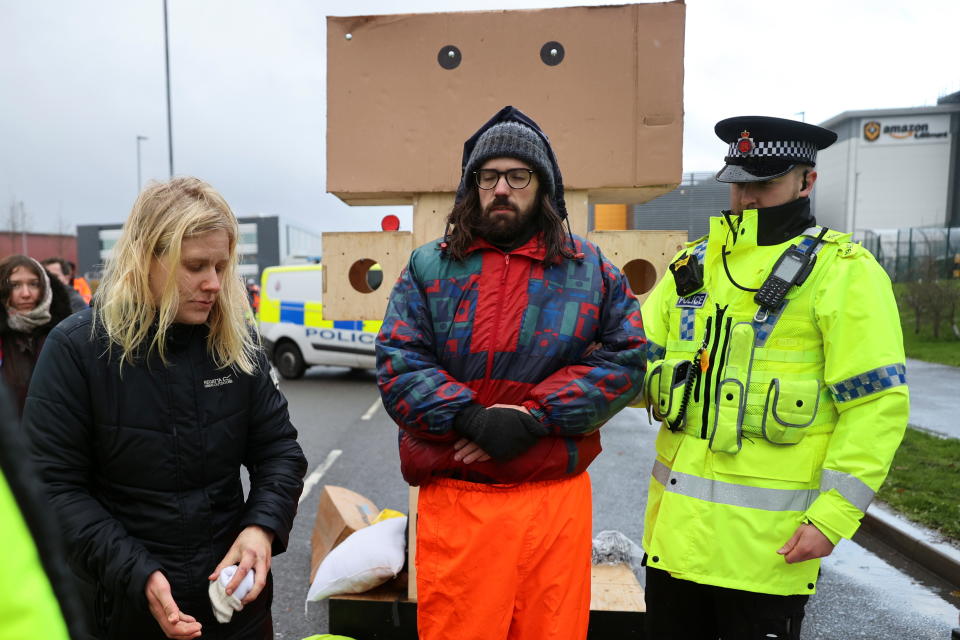 An Extinction Rebellion activist is detained by a police officer during a protest outside the Amazon Fulfilment Centre in Altrincham, near Manchester, Britain, November 26, 2021. REUTERS/Carl Recine