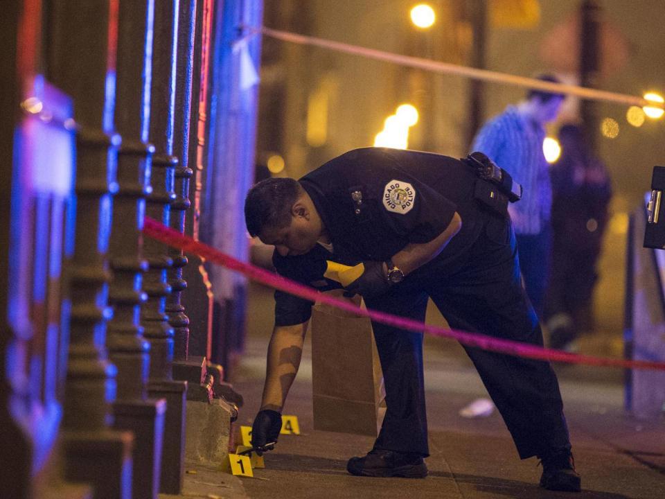 A Chicago police officer collects evidence at a crime scene. Chicago, with 2.7 million people, is the most violent large city in the US (Reuters)