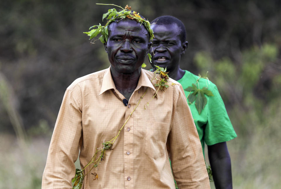 John Gafabusa, followed by Abiri Ntarwete, walks from the Mutyona natural sacred site near Buliisa, Uganda, Aug. 3, 2023. As TotalEnergies invests billions into oilfield development and acquires more and more land, Bagungu people who practice traditional beliefs worry the spiritual power of at least 32 sacred natural sites in Buliisa keeps deteriorating. (AP Photo/Hajarah Nalwadda)