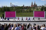 Models display a collection by the Branding and Design Academy METRICS during the Fashion Week at Zaryadye Park with the Kremlin Churches, the Spasskaya Tower and St. Basil's Cathedral in the background near Red Square in Moscow, Russia, Thursday, June 23, 2022. (AP Photo/Alexander Zemlianichenko)