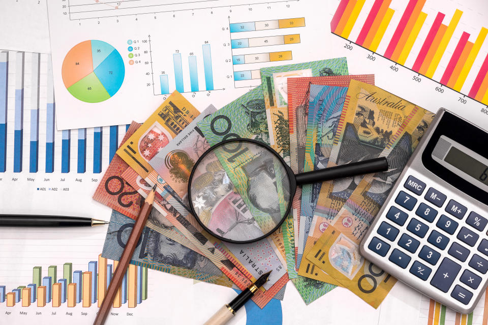 Business graphs with australian dollars, magnifying glass, pen and calculator