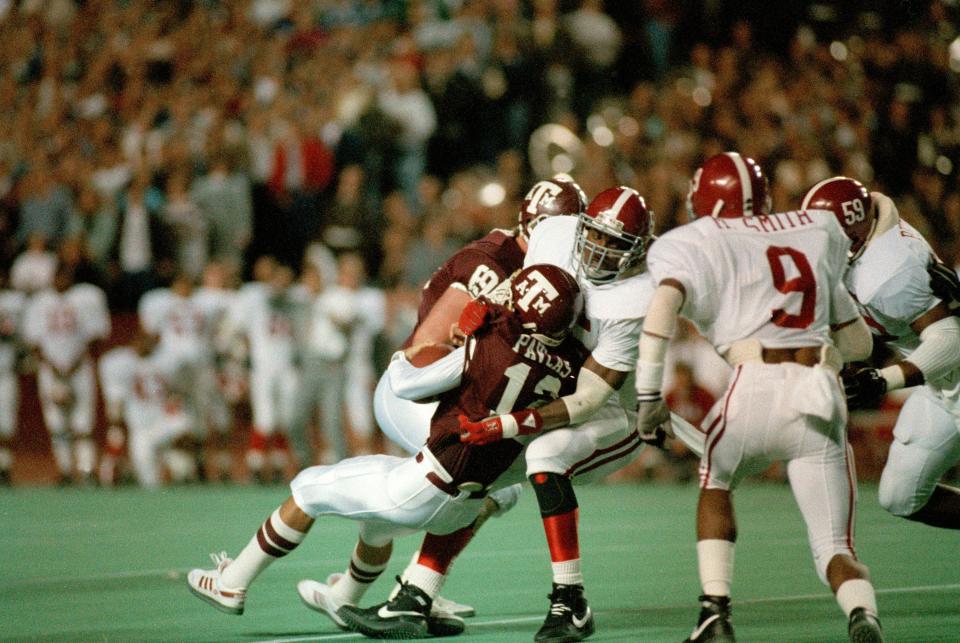 Texas A&M quarterback Lance Pavlas (12) is sacked for a 4-yard loss by Derrick Thomas (55) of the Alabama Crimson Tide on Dec. 1, 1988. The action is from the first quarter of the game, dubbed the "Hurricane Bowl" at College Station, Texas.
