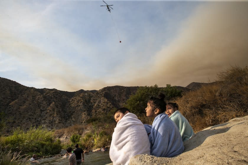 Azusa, CA, Sunday, August 16, 2020 - The Ranch2 Fire continues to burn nearby as Carlos Alvarado, 5, Shanti Mata, 6, and Aliah Alvarado, 6, dry off while swimming with others near a drainage pipe along the San Gabriel River. (Robert Gauthier / Los Angeles Times)