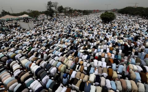 Rows of protesters kneel down in the street for Friday prayers - Credit: REUTERS/Akhtar Soomro