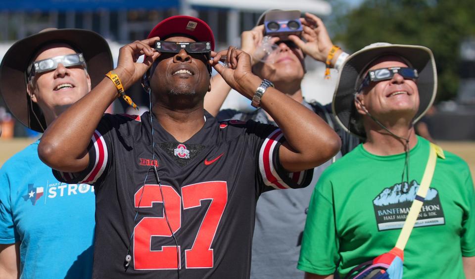 Jay Hoppe, David Bell Jr. and Dann DeMand, and Lloyd Peirce stop what there are doing to look at the eclipse during Austin City Limits weekend two day five at Zilker Park Saturday, Oct. 14, 2023.