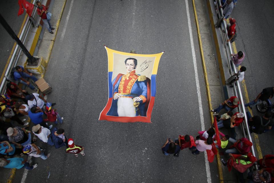 Supporters of President Nicolas Maduro holds a banner of Venezuela's independence hero Simon Bolivar during a rally celebrating 11 years of the Socialist Party of Venezuela' youth in Caracas, Venezuela, Thursday, Sept. 12, 2019. (AP Photo/Ariana Cubillos)