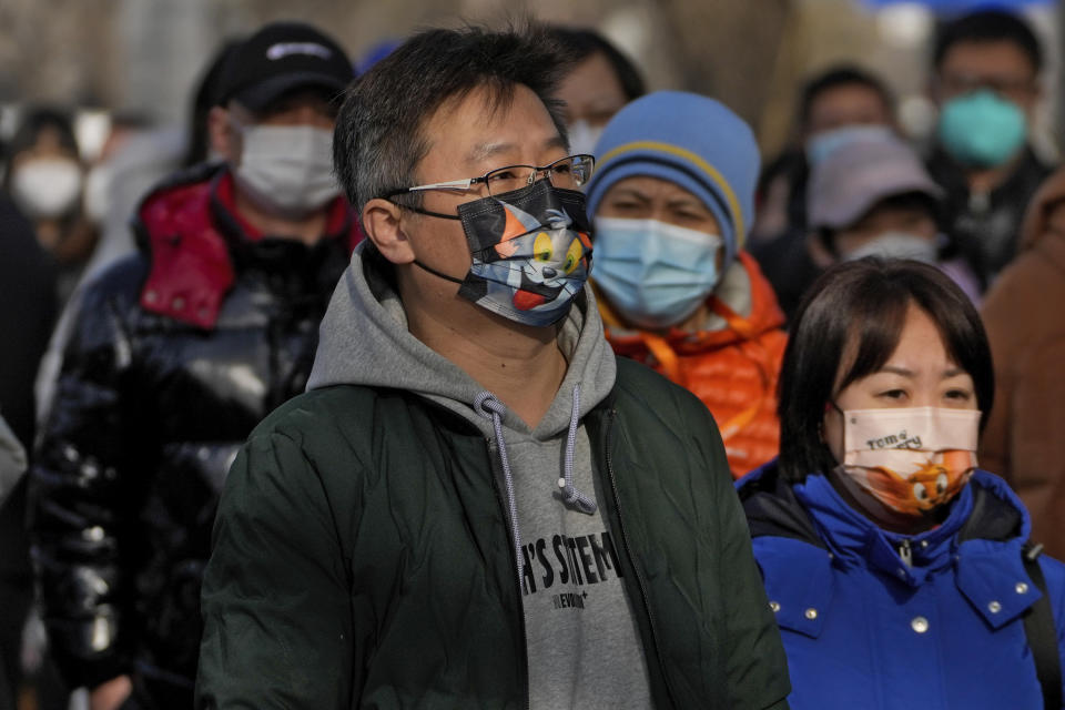 People wearing face masks walk on street in Beijing, Friday, Jan. 6, 2023. China is seeking to minimize the possibility of a major new COVID-19 outbreak during this month's Lunar New Year travel rush following the end of most pandemic containment measures. (AP Photo/Andy Wong)