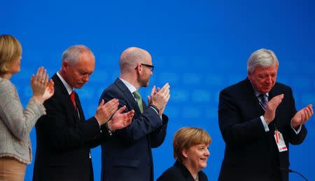 German Chancellor and leader of the Christian Democratic Union (CDU) Angela Merkel (2R) receives applause after delivering her speech during the CDU party congress in Karlsruhe, Germany December 14, 2015. REUTERS/Ralph Orlowski