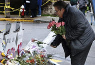 Colleen Cooper, of Shaler in suburban Pittsburgh, lays a single rose on each of the memorials for the eleven people fatally shot last week at the Tree of Life Synagogue after a service, on Saturday, Nov. 3, 2018, in Pittsburgh. About 100 people gathered in a cold drizzle for what was called a "healing service" outside the synagogue that was the scene of a mass shooting a week ago. (AP Photo/Keith Srakocic)