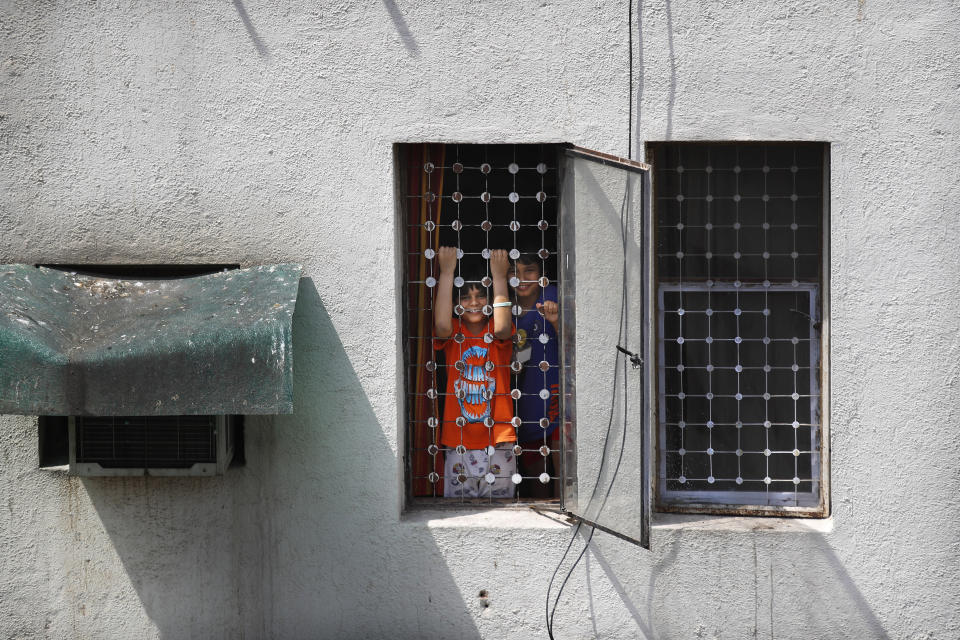 Uddhav Pratap Sanweria, 8, left, and his older brother Advait Vallabh, 9, play at the window of their home during a nationwide COVID-19 coronavirus lockdown in New Delhi, India, on Tuesday, April 14, 2020. Excited at first about school shutting down indefinitely, the brothers have now started missing being able to go outside. (AP Photo/Manish Swarup)