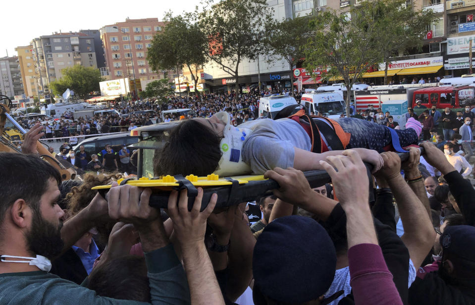 People carry a woman rescued from the debris of her collapsed house, in Izmir, Turkey, Friday, Oct. 30, 2020. A strong earthquake struck Friday in the Aegean Sea between the Turkish coast and the Greek island of Samos, collapsing buildings in the city of Izmir in western Turkey, and officials said at least six people were killed and scores were injured.(AP Photo/Ismail Gokmen)